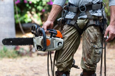 Elektrikli testereli adam manzarası bahçe için emniyet kemeri ve emniyet ipi kullanıyor. Doğaya karşı elektrikli testereli oduncu. Konsept bina, müteahhit, onarım, oduncu.