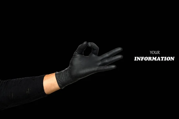 Hand okay sign. Man\'s hand in black rubber glove shows symbol of fine, making Gesture ok, yes on black background. Studio shot. High quality photo with space for text or logo.