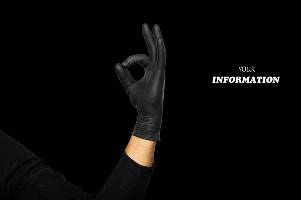 Hand okay sign. Man\'s hand in black rubber glove shows symbol of fine, making Gesture ok, yes on black background. Studio shot. High quality photo with space for text or logo.