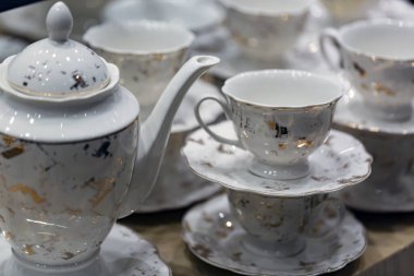 Bardakları ve çaydanlığı ahşap bir masaya koyun. Bardaklar ve tabaklar üst üste dizilmiş. Yüzeyin derinlerinde bir yığın kupa. Kutlama için restoranda boş bardaklar ve tabaklar. 