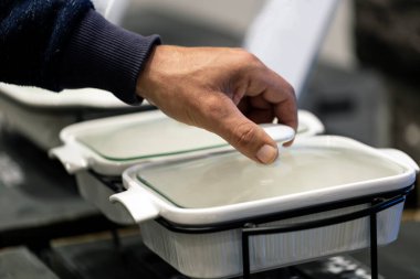 El açma kapağı. Bir adamın elindeki boş, yeni, beyaz tencereye yakından bak. Adam ev mutfağında lezzetli ve sağlıklı yemekler hazırlıyor. Bulanık arkaplan, seçici odak