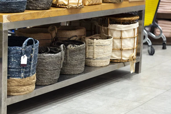 Laundry basket. Woven straw basket, container and boxes on a shelf in store. Bamboo weaving basket and brown Linen on shelf of rack background. Household decoration object made of natural eco material