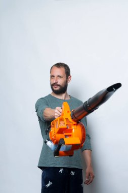 Stüdyo portresi beyaz arka planda kızgın suratlı bir el üfleme makinesi tutuyor. Beyaz tenli yakışıklı işçi kameraya bakıyor. İnsanlar, yaşam tarzı, teknoloji, bahçe ve bahçe bakımı kavramı