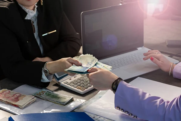 Muhasebecinin bilgisayara bir şeyler yazarken çekilmiş görüntüsü ve ofis çalışanlarına nakit para (ILS, şekel, dolar ve sterlin) veriyor. Ofiste İsrail şekellerini tutan kadın eller.
