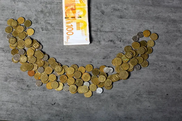 Banknotes and Coins Formed A Smiley Face emoji on the table. Financial success concept. Israeli Shekel Notes And coins, banknotes on the table. smiley face made out of agorot, ONE new Shekel coins