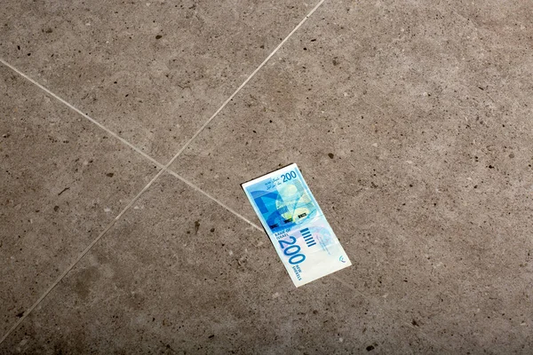 İsrail Ulusal İstihbaratı 'nın sokak zemininden 200 banknot, İsrail parası, İsrail' de iş. Para (ILS shekels) zemin parlak, gri kare karolar. Para bulmak, yerden gelen fatura.