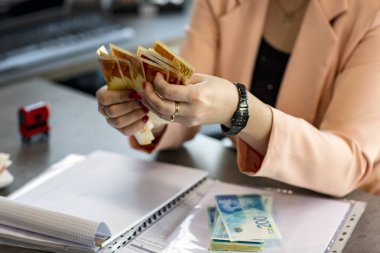 Kadın Eller İsrail 'in Yeni Şekelleri' nin para fanatiğini tutuyor. Masaya saçılmış para yığını. El 'in kesilmiş görüntüsü banknotları tutuyor. Seçici odaklanma. Para geçmişi. Mali konsept