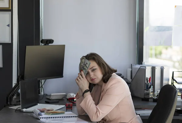 Depressed woman covering her face by the hands in office holding money in usa dollars banknotes at her face. Sad worried and desperate woman banking and accounting. finance, saving and banking concept