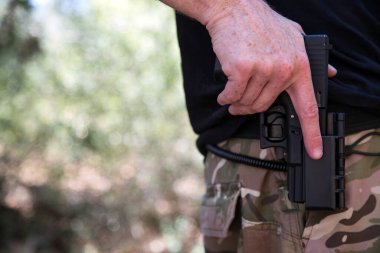 Katil ya da Amerikan polisi yeşil arka plan üzerinde metin konsepti için fotokopi alanı olan bir yere yakın duruyor. Polis, Kırpılmış El 9mm 'lik tabanca kılıfında. Kanun ve düzen. Ordu. Asker. Askeriyeden. Savaş