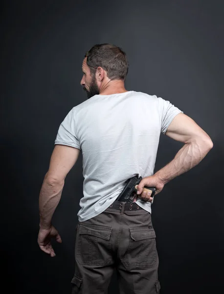 Arkadan bakıldığında, beyaz bir Amerikalı pantolonunun içine bir silah sokmuş. Sakallı suçlu, yasadışı, silahlı bir katil. İsrailli Rus erkek soygun konseptine bağlı olarak tabancaya uzanıyor