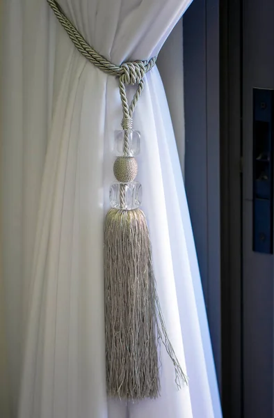用一根大的编织的绳子系着透明的白色窗帘 客厅里的窗帘系着奢华的领带 绳子绑在客厅里 窗帘用的漂亮装饰领带的窗户 — 图库照片