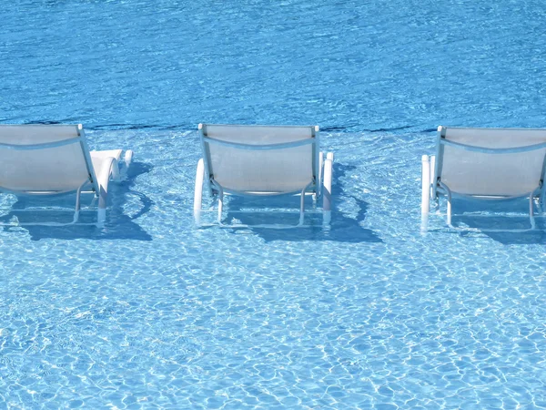 Tres chaise longue en la piscina Imagen De Stock