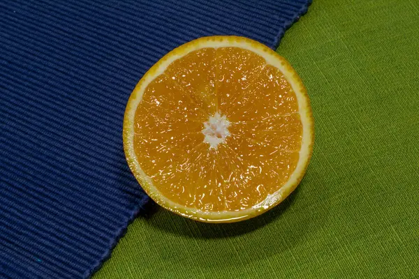 Ένα Πορτοκάλι Κομμένο Φέτες Πράσινο Και Μπλε Πανί — Φωτογραφία Αρχείου
