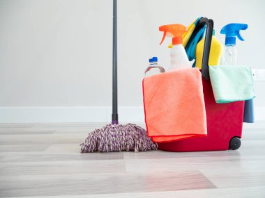 Beyaz bir kadın bir şişe su fırçasıyla temizlik yapıyor ve evini temizleme eldiveni ve mendilleriyle süpürüyor.