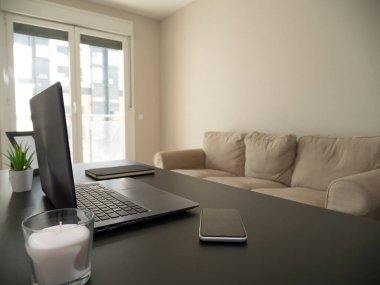 Beyaz mumlu siyah bir masanın üstünde dolabı olan bir odada dizüstü bilgisayar