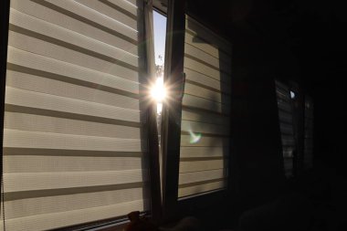 Yarı açık pencereden bir güneş ışığı huzmesi.