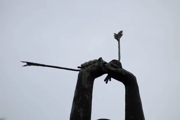 sculpture of hands against the sky