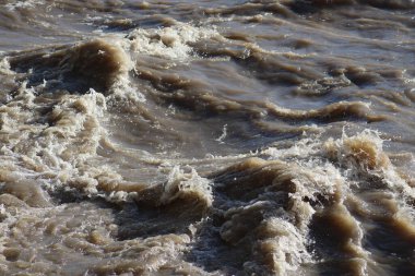 Öfkeli bir dağ nehrinin çamurlu suyu.