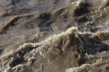 Öfkeli bir dağ nehrinin çamurlu suyu.