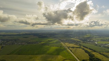  Güneş batarken bulutların arasından doğar ve bereketli toprakları aydınlatır.