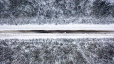  Deneyimli bir sürücü, ormanın içinden geçen donmuş bir yolda, üst manzaralı bir karavanla sürüyor.