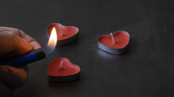 stock image a man with a lighter lights candles in the form of hearts for valentines day