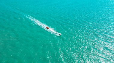 Çocuklar açık denizdeki dalgalarda yüksek hızda uçuyor şişirilebilir plastik muz, hava fotoğrafçılığı.