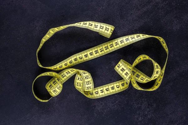 meter yellow tape for sewing and needlework lies on the black surface