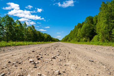 Kırsal yerleşimlere giden toprak yol. Kırsal yol ve açık mavi gökyüzü.