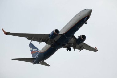 Bir yolcu uçağı havalanıyor ve bulutlu bir havada gökyüzünde uçuyor. Rus bayrağını dalgalandıran uçak..