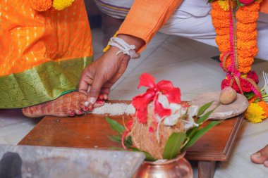 Geleneksel Hindu düğün ritüelinin yakın planında damat pirinci gelin mehndi süslemeli ayaklarının yanına yerleştirir ve refahı simgeler..