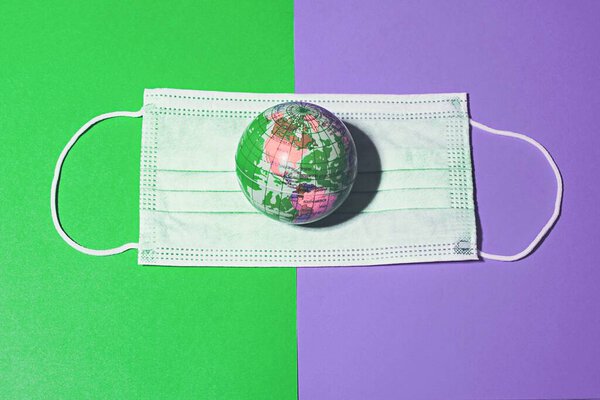 Surgical Face Mask and Globe model in a colorful background. Coronavirus Concept