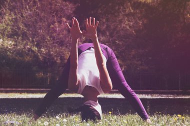 Parktaki kadın amuda kalkıyor.