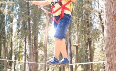 Çocuk macera parkında ipte yürüyor..