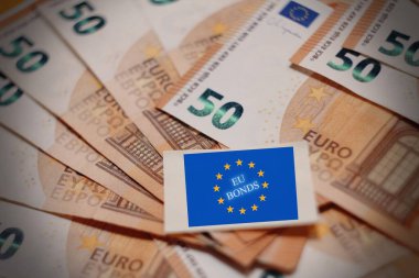 AB bayraklarıyla kaplanmış AB Tahvilleri metni. Avrupa borç araçları, piyasa finansmanı ve ekonomi politikalarının kavramsal imajı.