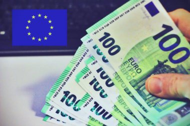 Arka planda klavyesi olan 100 avroluk el ele tutuşmalar.