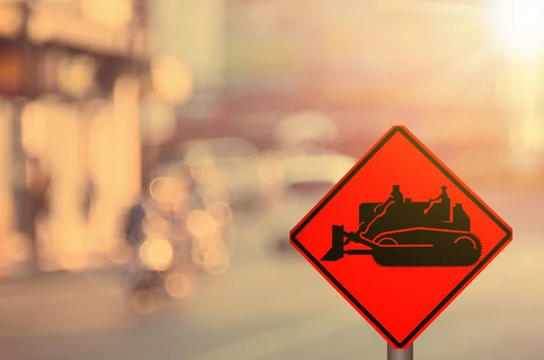 Traffic sign,construction tractor sign on blur traffic road abstract background. — Stock Photo, Image