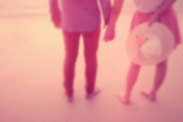 Rozostření pár se drží ruku na sunset beach abstraktní pozadí. — Stock fotografie