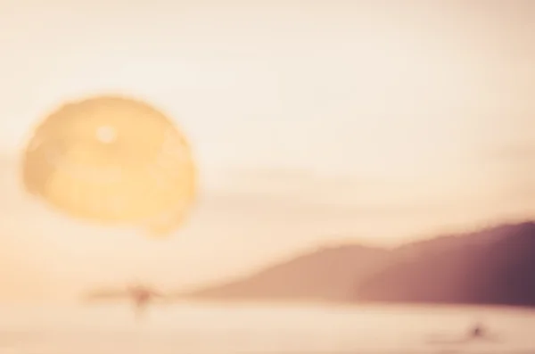 模糊的人玩降落伞船在热带海滩抽象背景 — 图库照片