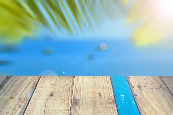 Motion flou plage tropicale avec feuille de palmier sur fond de vieux bois de table vide — Photo
