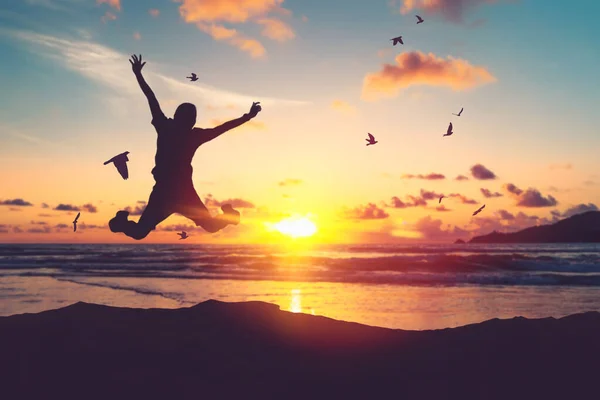 鳥が日没の空の抽象的な背景に飛んで熱帯のビーチでジャンプ幸せな男 自由は良いと旅行の冒険の概念を感じる ヴィンテージトーンフィルターエフェクトカラースタイル — ストック写真