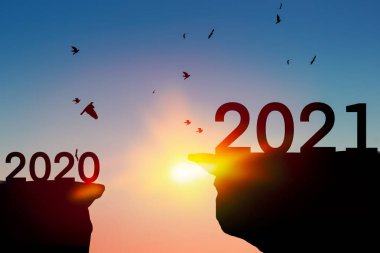 2021 yeni yıl konsepti. Kuşlar gün batımında gökyüzünde uçuyor. Dağın tepesinde..