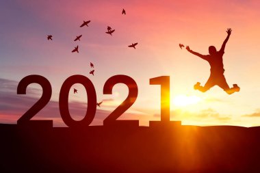 Silüet adam atlıyor ve kuşlar gün batımında dağın tepesinde gökyüzünde uçuyor ve sayı 2021 gibi soyut bir arka plan. Mutlu yıllar ve bayram kutlamaları. Klasik ton filtresi renk biçimi.