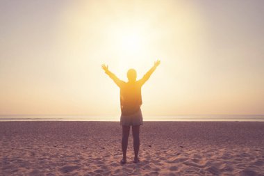 Sahilde ve adada, günbatımında gökyüzünde yükselen kadın mekânını kopyalayın. Özgürlük ve seyahat macera konsepti. Klasik ton filtre efekti renk biçimi.