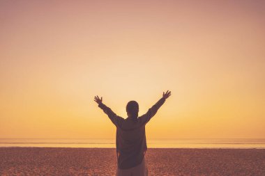 Sahilde ve adada, günbatımında gökyüzünde yükselen kadın mekânını kopyalayın. Özgürlük ve seyahat macera konsepti. Klasik ton filtre efekti renk biçimi.