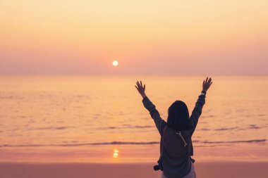 Sahilde ve adada, günbatımında gökyüzünde yükselen kadın mekânını kopyalayın. Özgürlük ve seyahat macera konsepti. Klasik ton filtre efekti renk biçimi.