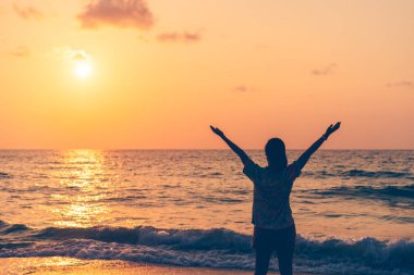 Sahilde ve adada, günbatımında gökyüzünde yükselen kadın mekânını kopyalayın. Özgürlük ve seyahat macera konsepti. Klasik ton filtre efekti renk biçimi.