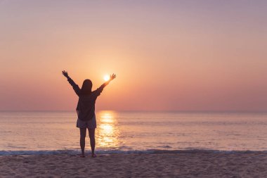 Sahilde ve adada, günbatımında gökyüzünde yükselen kadın mekânını kopyalayın. Özgürlük ve seyahat macera konsepti. Klasik ton filtre efekti renk biçimi.