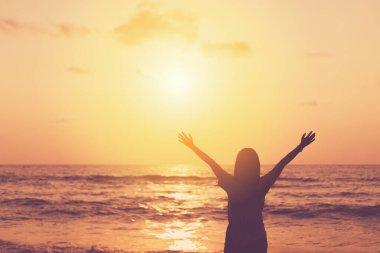 Sahilde ve adada, günbatımında gökyüzünde yükselen kadın mekânını kopyalayın. Özgürlük ve seyahat macera konsepti. Klasik ton filtre efekti renk biçimi.