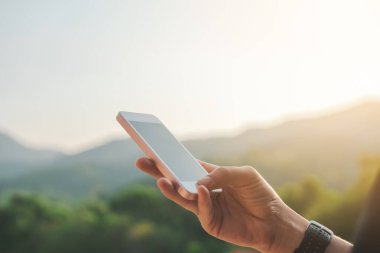 Kadın eli dağın tepesinde akıllı telefon kullanıyor, gökyüzü soyut arkaplanı var. Uzay teknolojisi ve seyahat doğası tatil konseptini kopyalayın. Klasik ton filtre efekti renk biçimi.